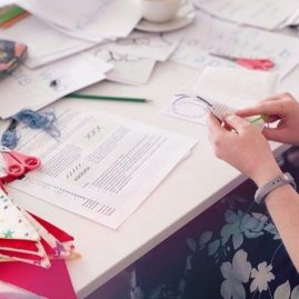 Lady's hands at a table working on a cross stitch project